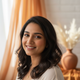 Smiling South Asian woman's authentic headshot portrait with a warm, approachable expression, against a blurred background in